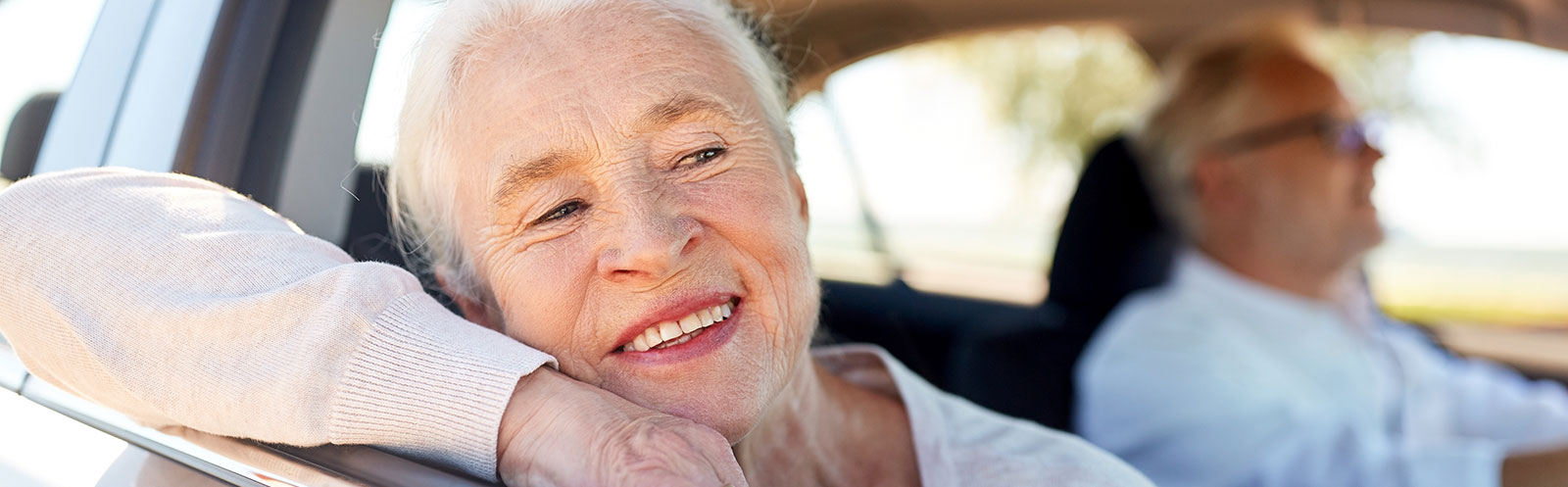 Une passagère souriante à l’avant d’une voiture conduite par un pilote